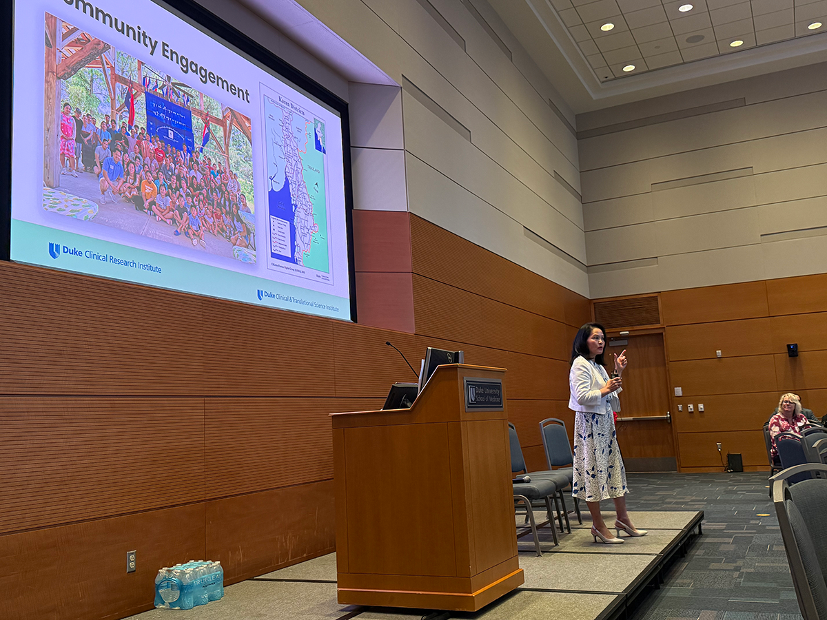 Lilly Chen on a dias speaking with a microphone