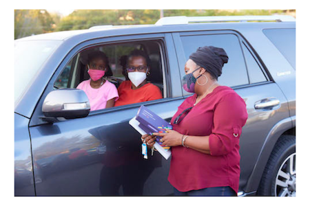 Kenisha Bethea speaking to community members in their car during an ethnodrama event