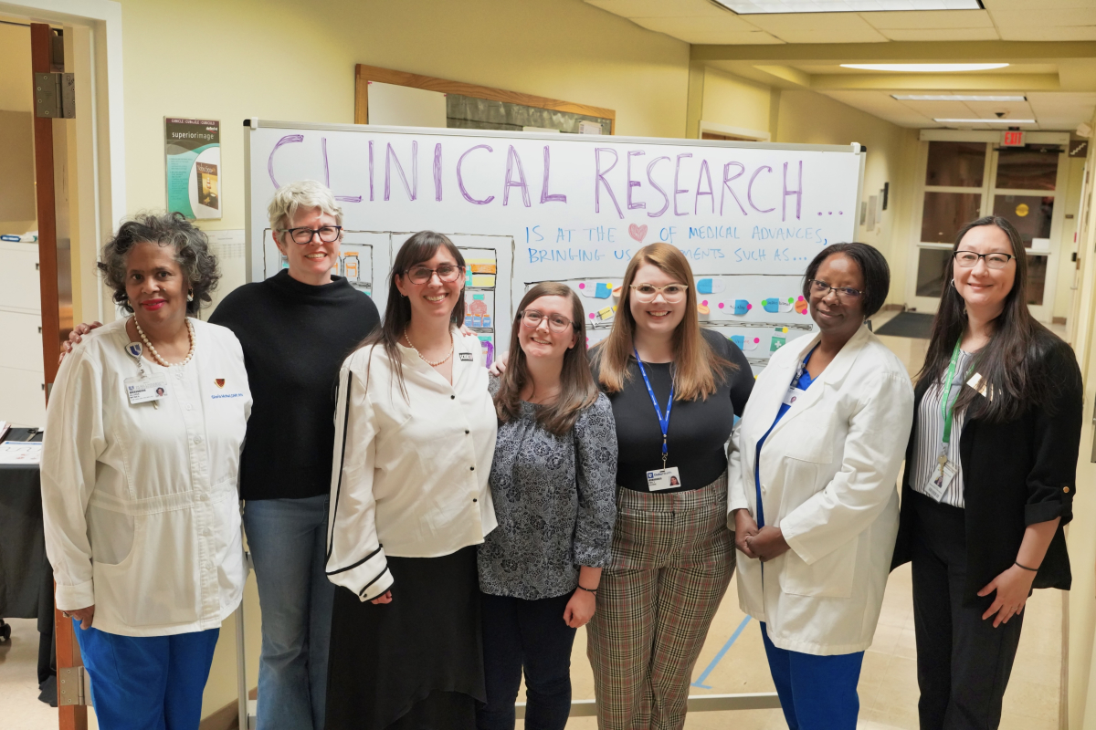 Staff members with CTSI and partners stand in front of a white board reading "clinical research" at the open house event for the new Durham Early College of Health Sciences