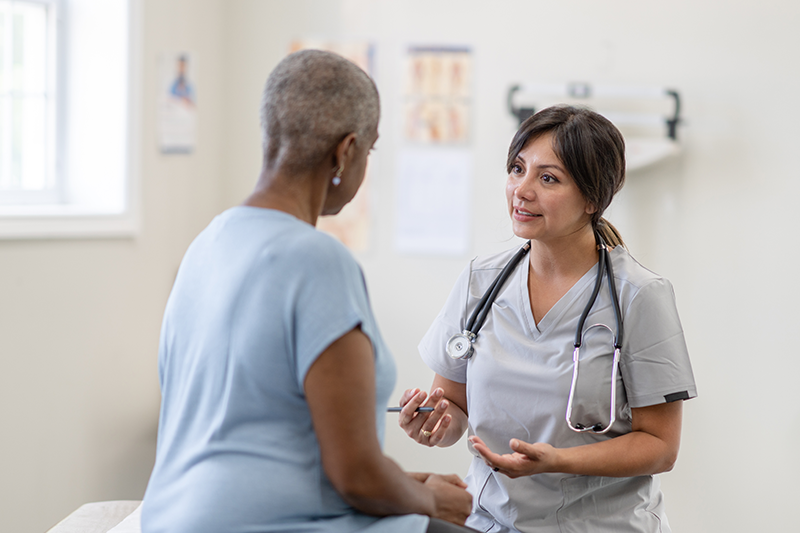 Healthcare provider speaking with a patient in an exam room. 
