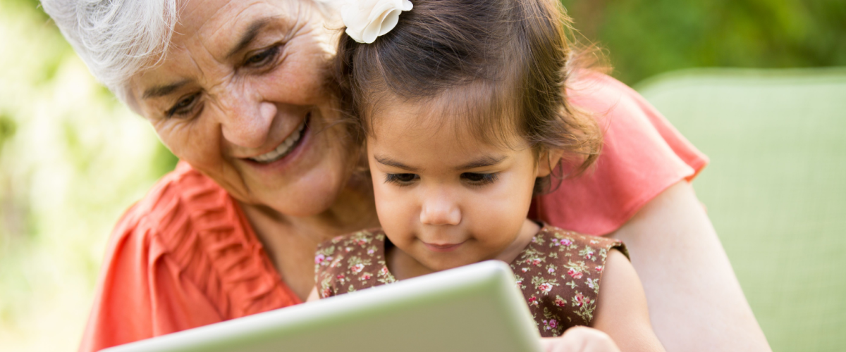 Senior woman and young child looking at tablet together.