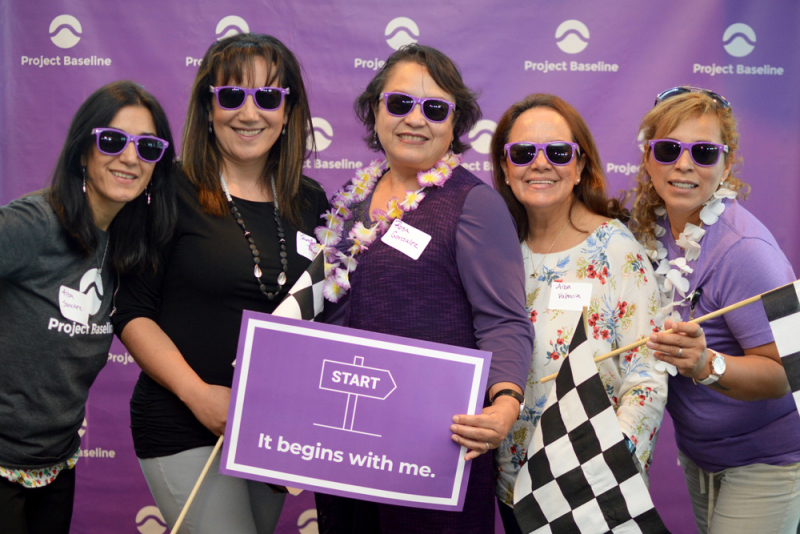 Group of people with matching sunglasses and sign at Project Baseline event.