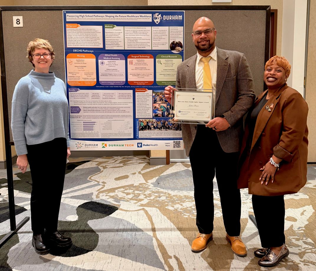 Poster presenters in front of their poster with the award. 