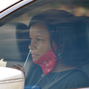 Woman giving herself a nasal swab in her car at drive-in COVID testing site.