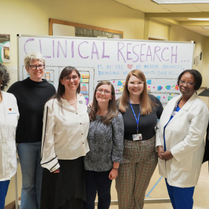 Staff members with CTSI and partners stand in front of a white board reading "clinical research" at the open house event for the new Durham Early College of Health Sciences